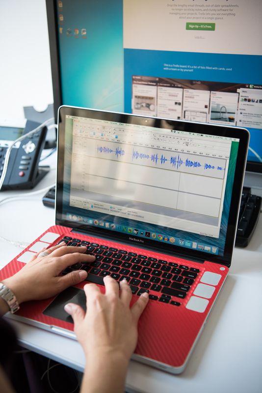 Person dictating into a laptop microphone while software transcribes speech to text