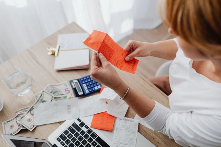 Person at a desk with a calculator and receipts working out AI subscription and usage costs