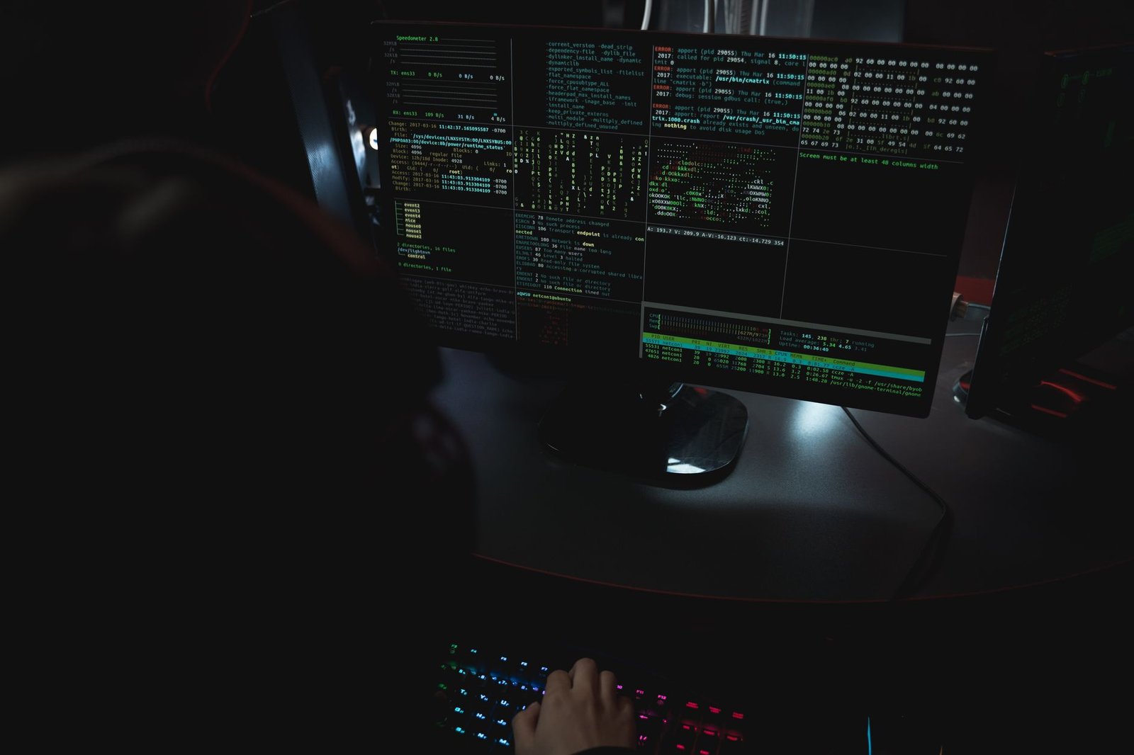 Developer workstation with code displayed on dark terminal monitors