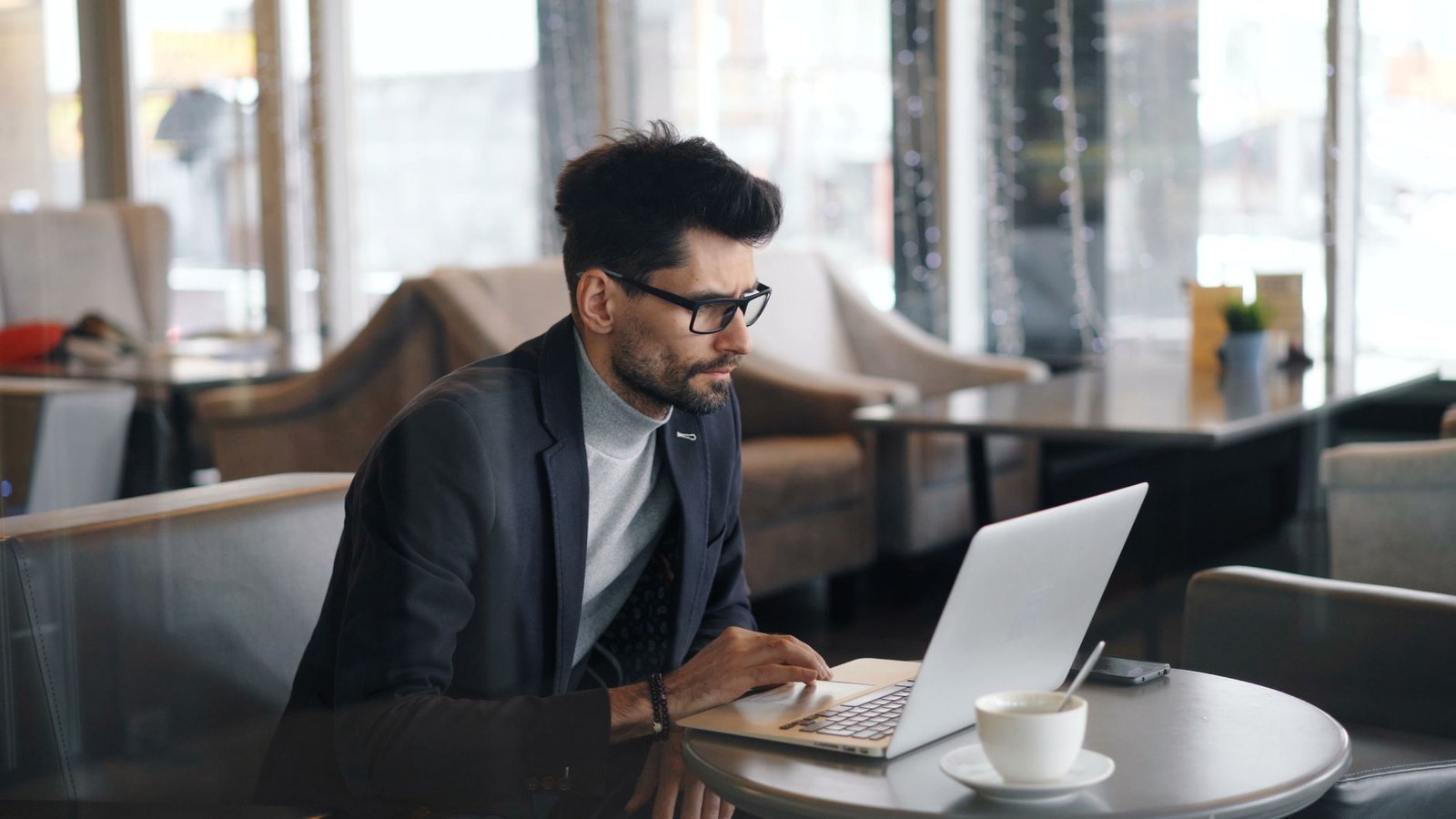Person working on a laptop in a cafe, the kind of multitasking Comet's AI assistant aims to speed up