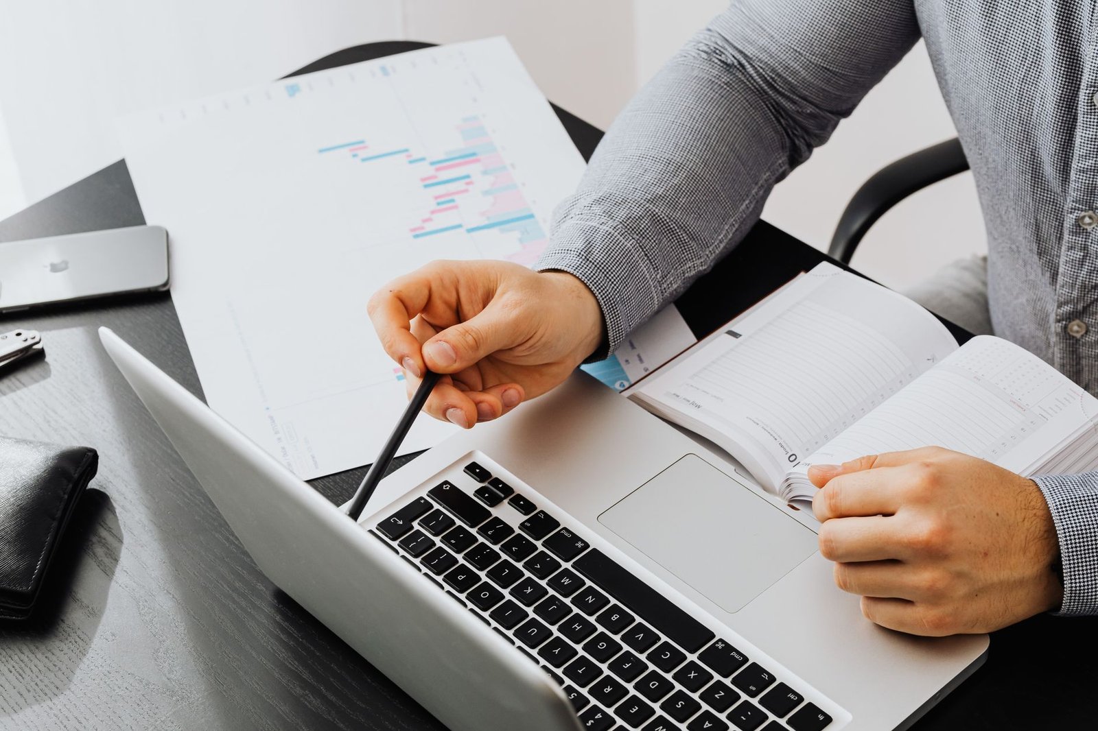 Professional reviewing a stack of documents with a laptop