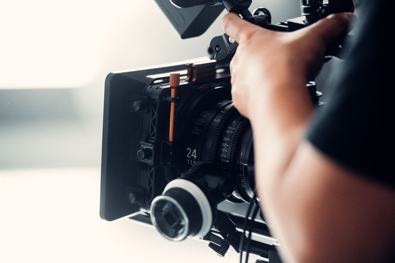 Operator working a professional video camera indoors during a filming session