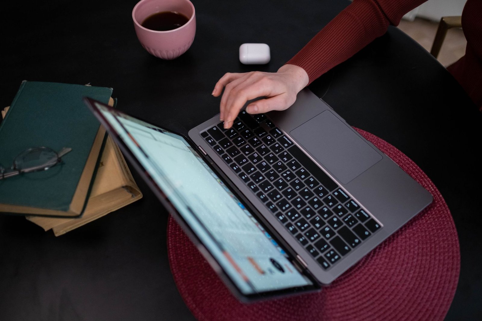A writer editing long-form content on a laptop with coffee and books nearby